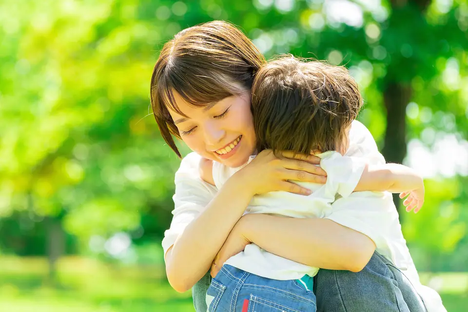 公園で子どもを抱きしめ、笑顔を見せる母親
