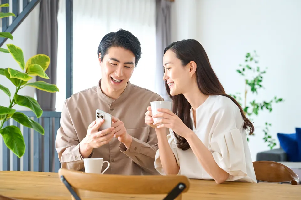スマートフォンを見ながら笑顔で話す夫婦