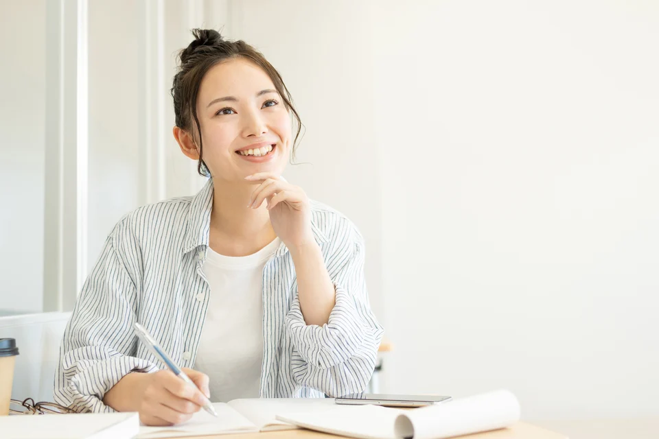 明るい部屋でテキストとノートを広げて学習する女性
