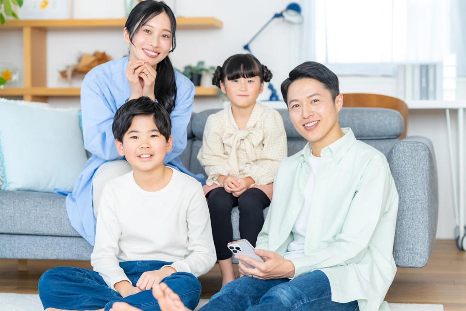 家族が自宅のソファで寄り添い、笑顔でくつろいでいる様子